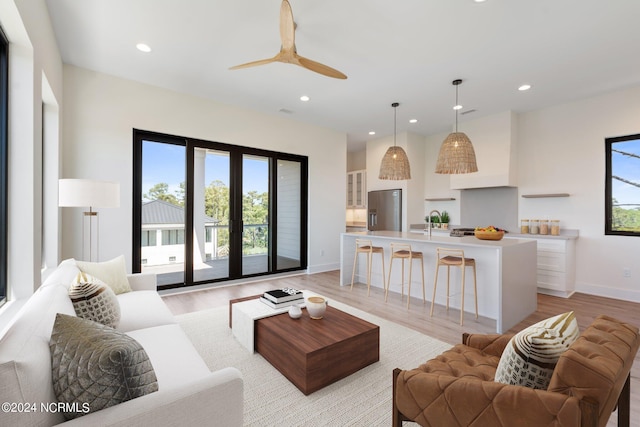 living room featuring french doors, light hardwood / wood-style floors, ceiling fan, and sink