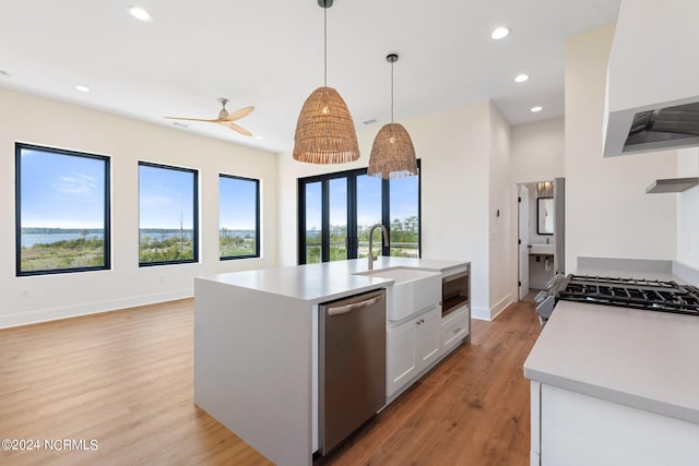 kitchen featuring appliances with stainless steel finishes, white cabinetry, decorative light fixtures, light hardwood / wood-style flooring, and custom range hood