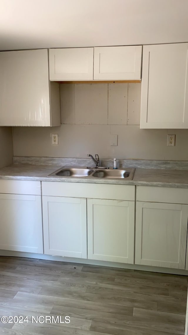 kitchen with light hardwood / wood-style floors, white cabinets, and sink