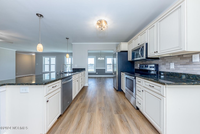 kitchen featuring white cabinets, tasteful backsplash, decorative light fixtures, stainless steel appliances, and light hardwood / wood-style flooring