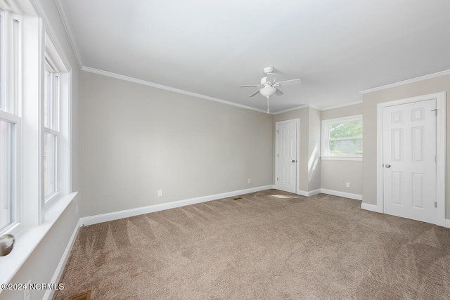 empty room featuring dark colored carpet, ceiling fan, and ornamental molding