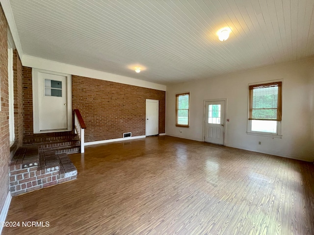 unfurnished room with dark hardwood / wood-style flooring and brick wall