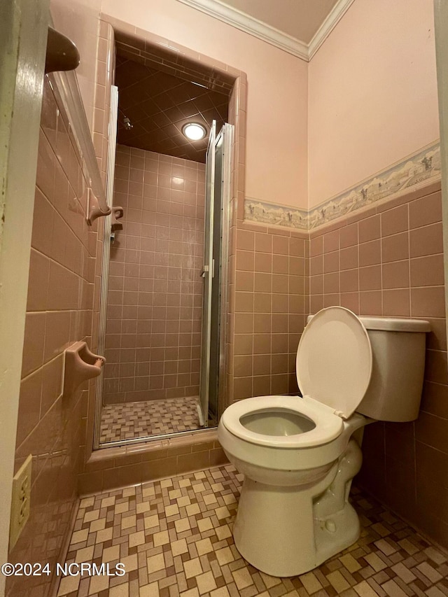 bathroom featuring tile walls, ornamental molding, a shower with shower door, tile flooring, and toilet