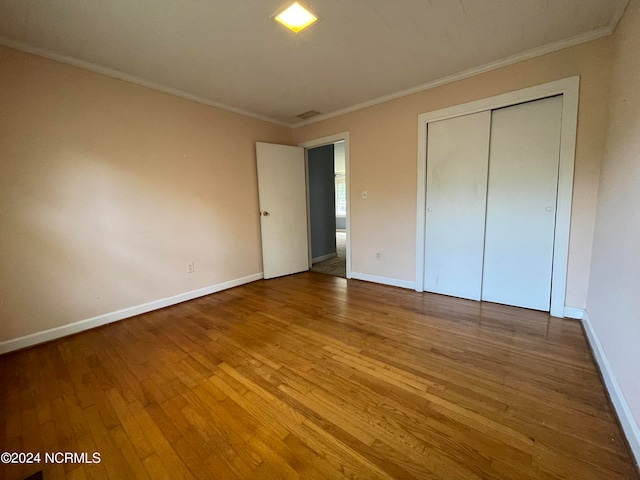 unfurnished bedroom featuring a closet, light wood-type flooring, and ornamental molding