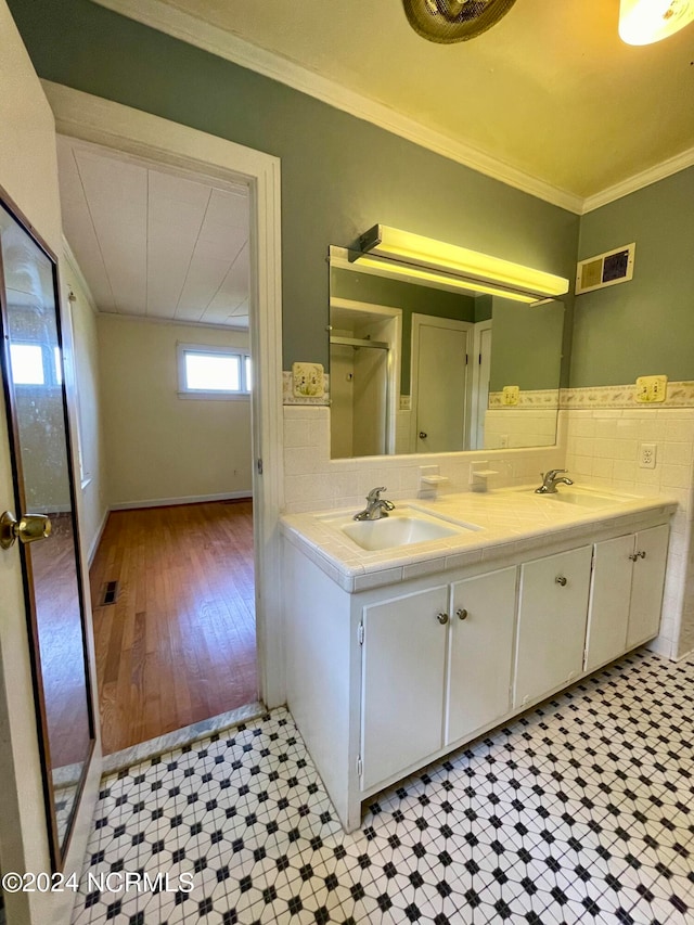 bathroom with crown molding, double vanity, tile floors, and tasteful backsplash