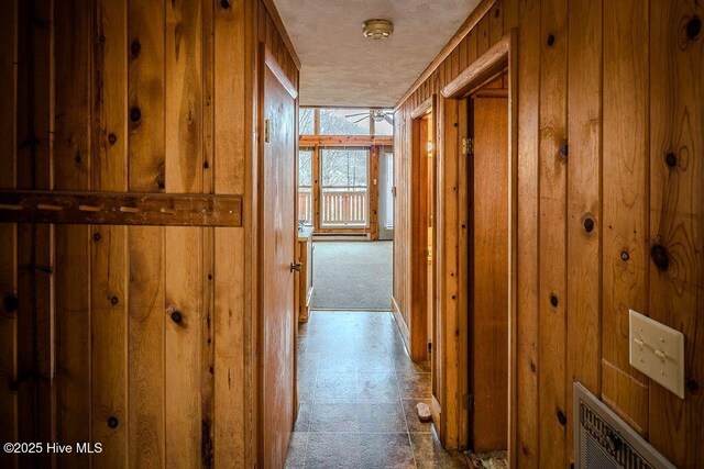 kitchen with wooden walls, a wood stove, dark carpet, white appliances, and kitchen peninsula