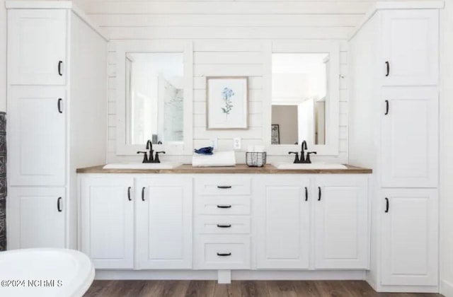 bathroom featuring dual bowl vanity and hardwood / wood-style flooring