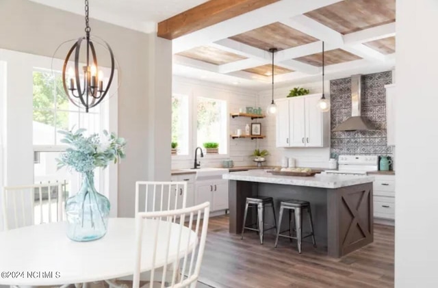 kitchen with beamed ceiling, a center island, wall chimney range hood, white cabinetry, and dark hardwood / wood-style floors