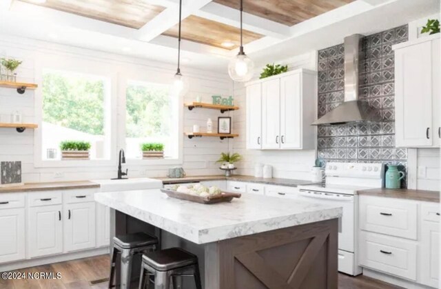 kitchen with a kitchen island, electric range, dark wood-type flooring, coffered ceiling, and wall chimney exhaust hood