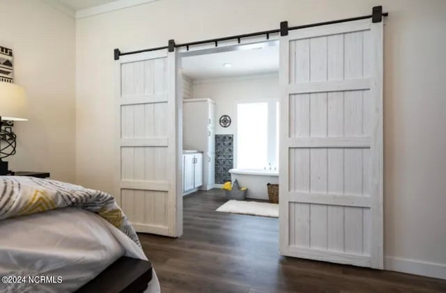 bedroom featuring crown molding, a barn door, and dark hardwood / wood-style floors