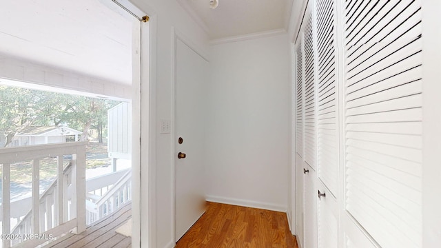 corridor featuring a healthy amount of sunlight, hardwood / wood-style flooring, and crown molding