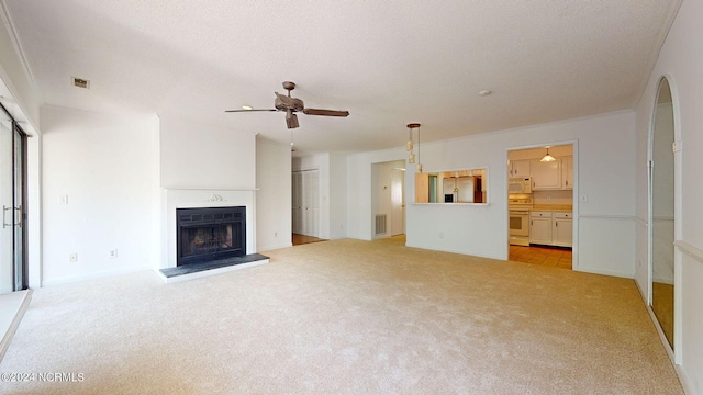 unfurnished living room with a textured ceiling, ceiling fan, light carpet, and ornamental molding