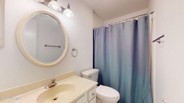 bathroom with vanity, toilet, and a textured ceiling