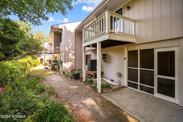 exterior space with central air condition unit, a patio area, a wall unit AC, and a balcony