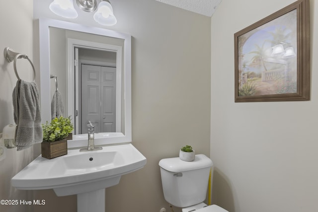 half bathroom featuring a sink, a chandelier, and toilet
