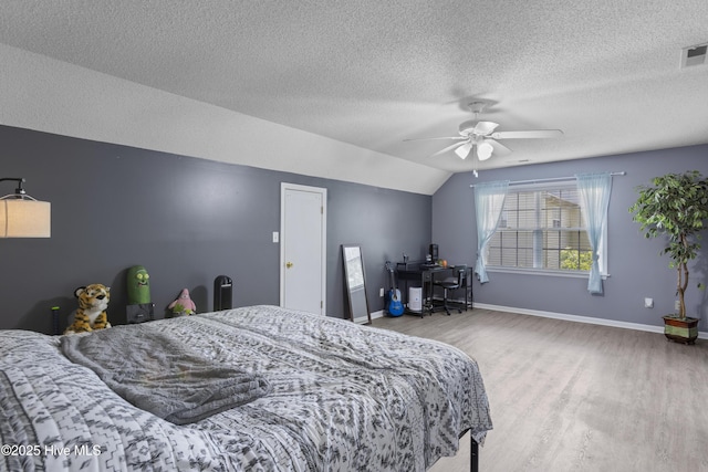 bedroom featuring wood finished floors, a textured ceiling, vaulted ceiling, a ceiling fan, and baseboards