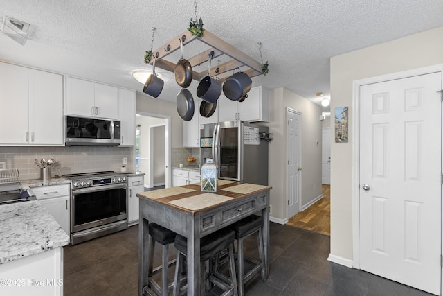167 Dockside Dr, Jacksonville, NC 28546 - kitchen featuring stainless steel appliances, white cabinets, tasteful backsplash, a textured ceiling, and light stone countertops