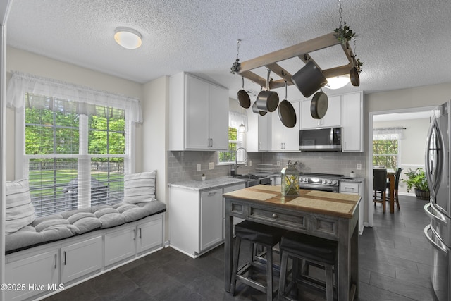 167 Dockside Dr, Jacksonville, NC 28546 - kitchen with appliances with stainless steel finishes, a sink, a textured ceiling, decorative backsplash, and white cabinets