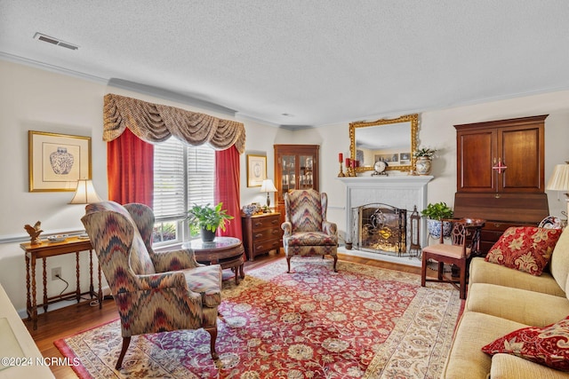 living room with a fireplace, hardwood / wood-style floors, a textured ceiling, and ornamental molding