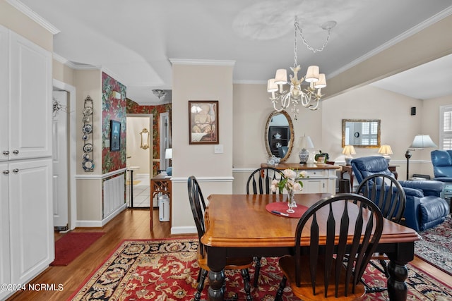 dining area featuring hardwood / wood-style flooring, an inviting chandelier, crown molding, and vaulted ceiling