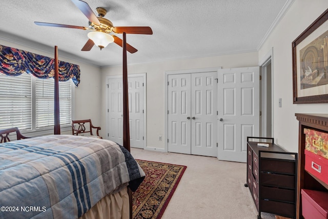 carpeted bedroom with ceiling fan, a textured ceiling, and multiple closets