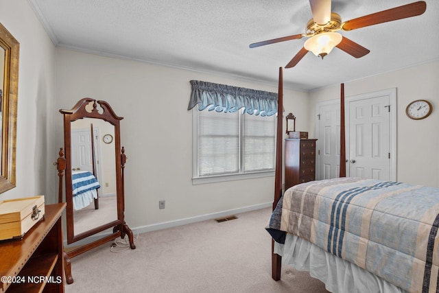 carpeted bedroom with a closet, a textured ceiling, ceiling fan, and crown molding