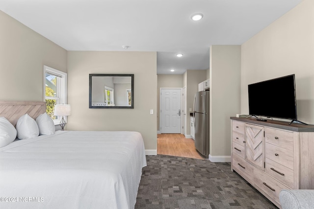 bedroom with stainless steel refrigerator and dark wood-type flooring