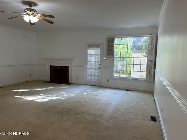 unfurnished living room featuring ornamental molding, carpet flooring, a brick fireplace, and ceiling fan