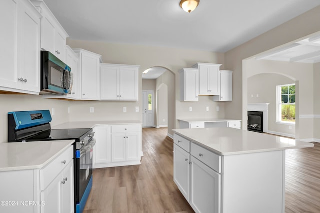 kitchen with black electric range, white cabinetry, light wood-type flooring, and a kitchen island