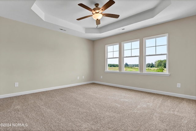 carpeted empty room with ceiling fan and a raised ceiling