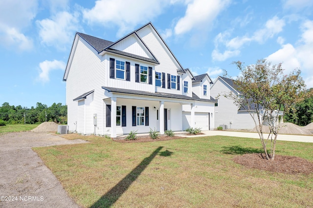 view of front of home with cooling unit, a front yard, covered porch, and a garage