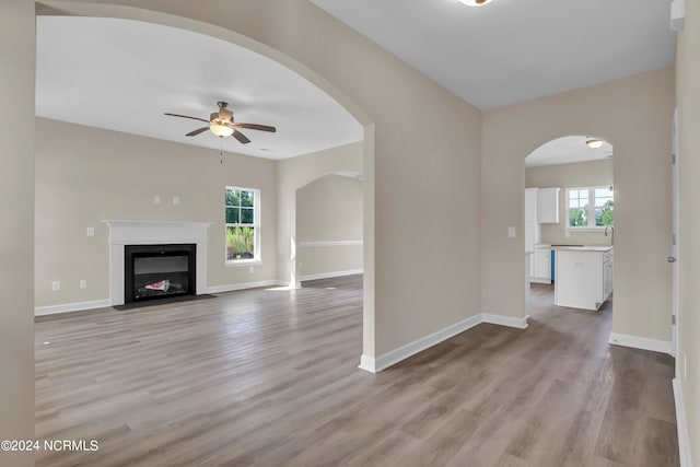 unfurnished living room with ceiling fan, light wood-type flooring, and a wealth of natural light