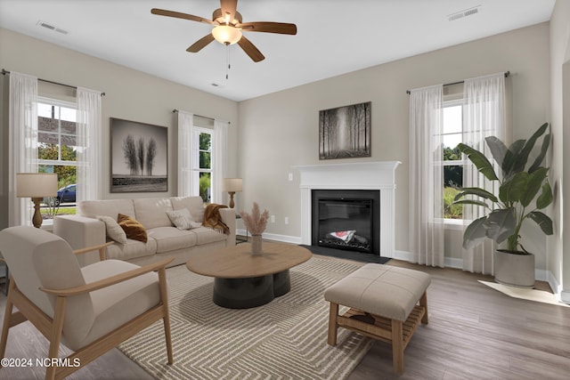 living room with a wealth of natural light, wood-type flooring, and ceiling fan