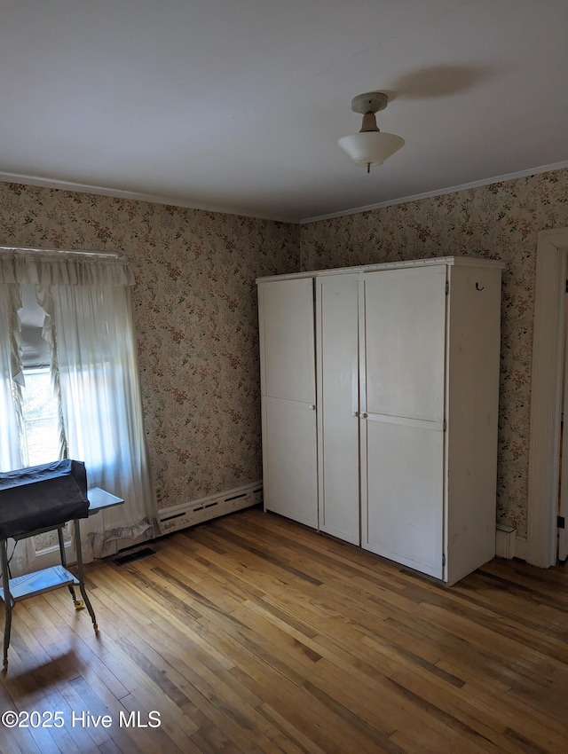 unfurnished bedroom with wallpapered walls, wood-type flooring, and crown molding