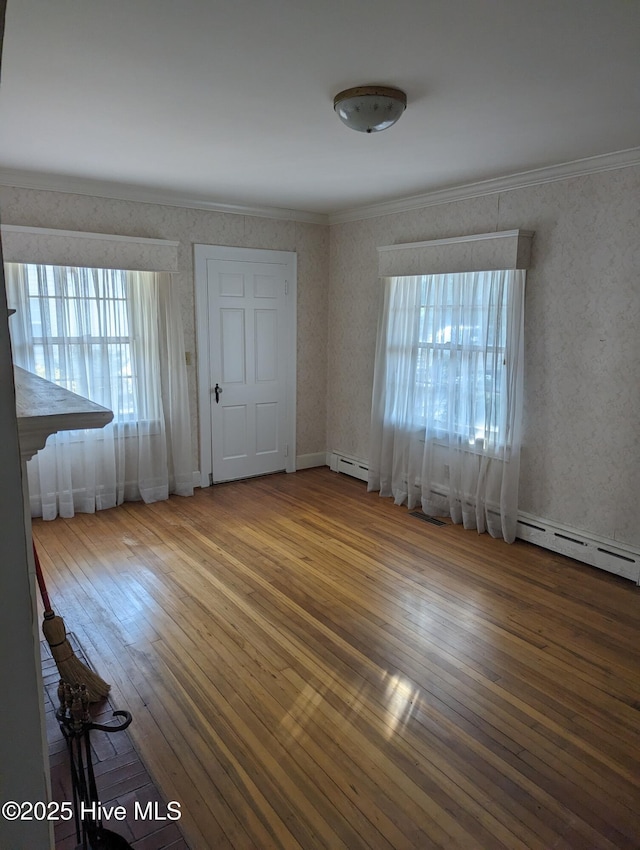 empty room with wallpapered walls, a baseboard radiator, ornamental molding, and hardwood / wood-style floors