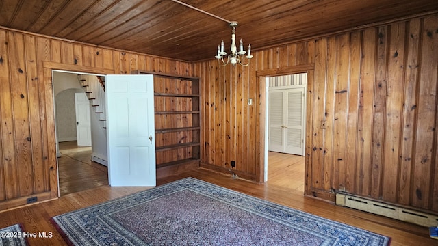 interior space with wooden ceiling, dark wood-style floors, a baseboard radiator, and wooden walls