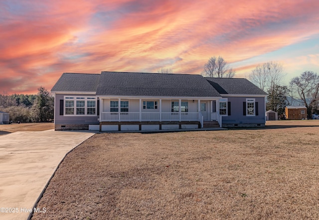 ranch-style home featuring covered porch and a storage shed