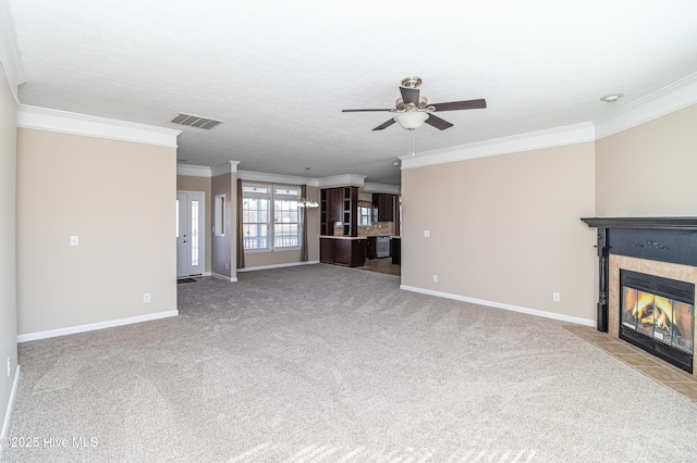 unfurnished living room with a tile fireplace, light carpet, ceiling fan, and ornamental molding