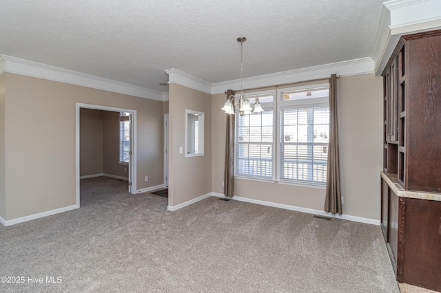 carpeted empty room featuring a chandelier, a textured ceiling, and ornamental molding