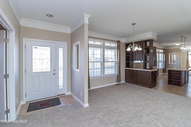 carpeted foyer entrance with crown molding and an inviting chandelier