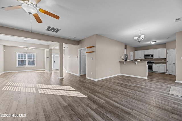 unfurnished living room featuring ceiling fan with notable chandelier and dark hardwood / wood-style floors