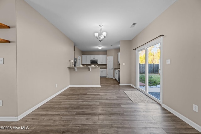 unfurnished living room with hardwood / wood-style floors and an inviting chandelier