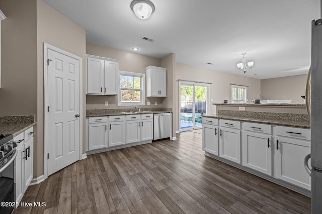 kitchen featuring appliances with stainless steel finishes, dark hardwood / wood-style flooring, sink, a chandelier, and white cabinetry