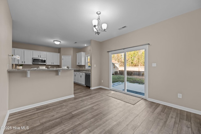 kitchen featuring white cabinetry, light stone countertops, a kitchen breakfast bar, kitchen peninsula, and dishwashing machine