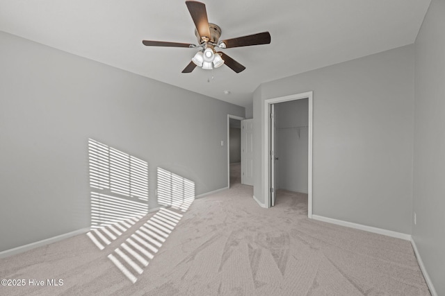 unfurnished bedroom with light carpet, a closet, a spacious closet, and ceiling fan