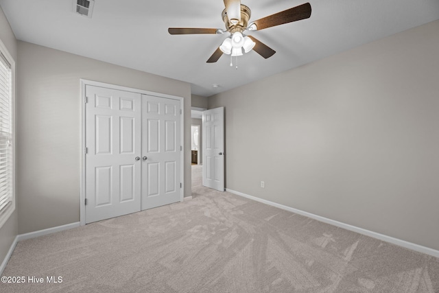 unfurnished bedroom with ceiling fan, light colored carpet, and a closet