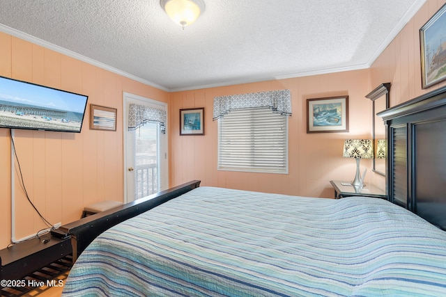 bedroom with wooden walls, a textured ceiling, and ornamental molding