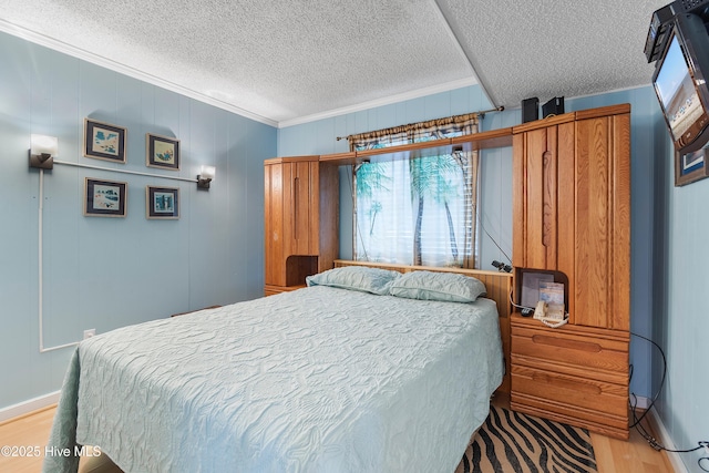 bedroom with light wood-type flooring, wooden walls, crown molding, and a textured ceiling