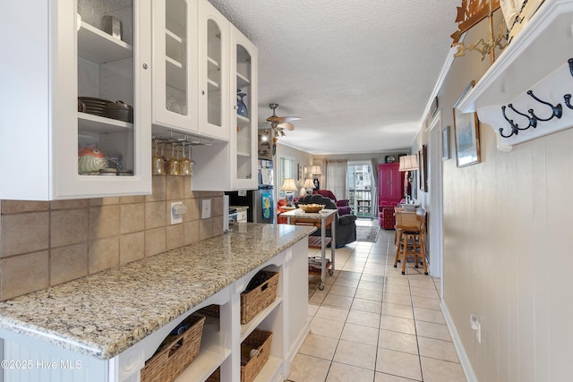 kitchen with ceiling fan, light stone countertops, white cabinetry, and light tile patterned flooring