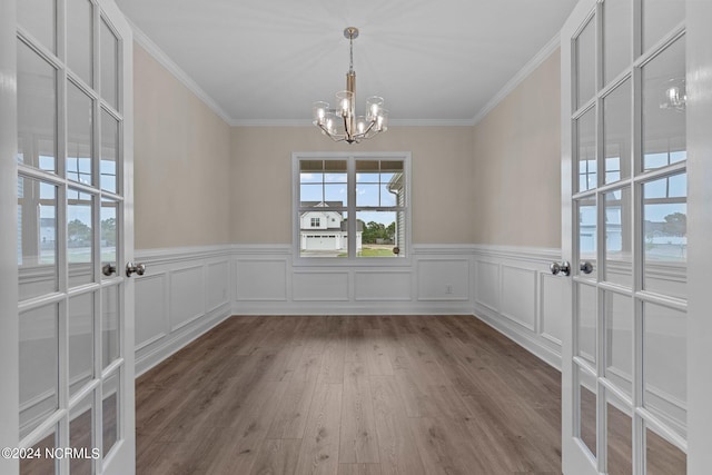 unfurnished dining area featuring light hardwood / wood-style flooring, ornamental molding, and a chandelier